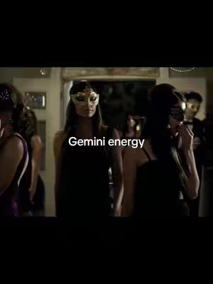 The image shows a group of people at a party. The focus is on a woman in the middle wearing a gold mask. There is text overlayed that reads "Gemini energy".