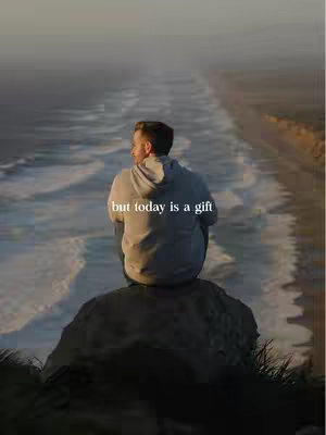 A man sits on a rock, facing away from the camera, overlooking a calm ocean. The sky is overcast, with the text overlayed.