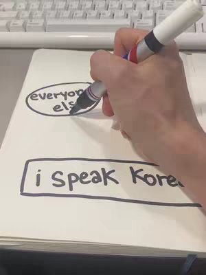 A hand holding a white marker writes on a notepad.  The notepad has handwritten text inside of a drawn circle and rectangle. A computer keyboard is in the top of the frame.