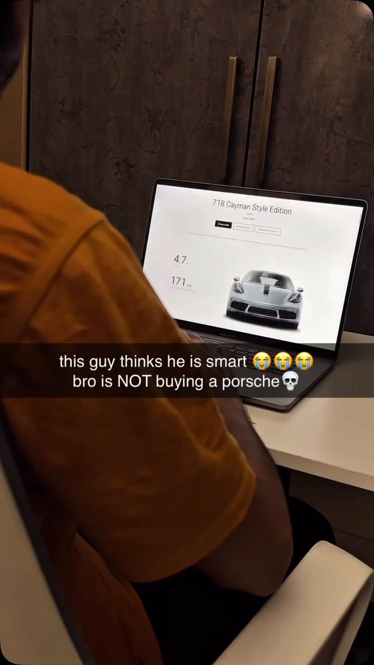 A person in an orange shirt is seated at a white table, with a laptop open in front of them. The laptop displays a webpage featuring a silver Porsche and data. The background includes a patterned brown wall. Text overlays on the image, commenting on the website content and the car's affordability.