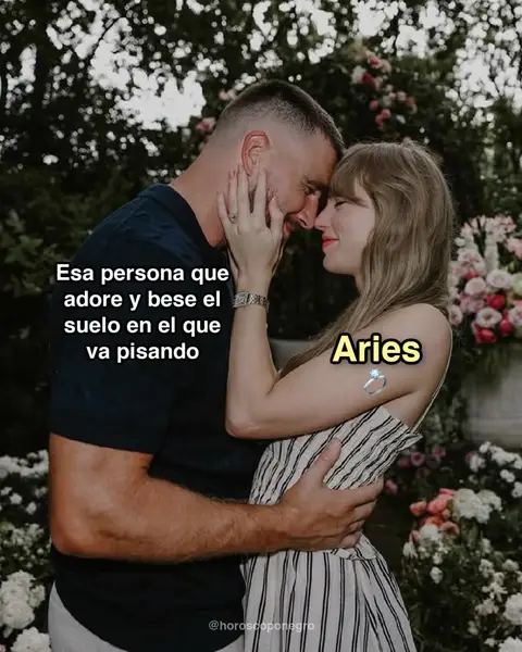 A romantic image of a couple in an embrace, with a background of greenery and flowers. The man, on the left, is wearing a dark shirt and embracing the woman. The woman's hand is on his face. A text overlay with the word "Aries" and an engagement ring appears on the image.