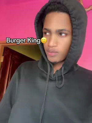 A young man wearing a black hoodie with the hood up, set against a pink wall. A text overlay with a smiling emoji is placed on the image.