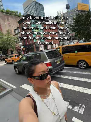 A selfie-style shot taken in a city. The creator, a person with dark hair wearing sunglasses and a white tank top, is standing on a crosswalk with cars in the background. A text overlay reads: "my favorite animal is me when i've finally lost my patience and i can finally show them why my family and friends avoid me when i'm mad".