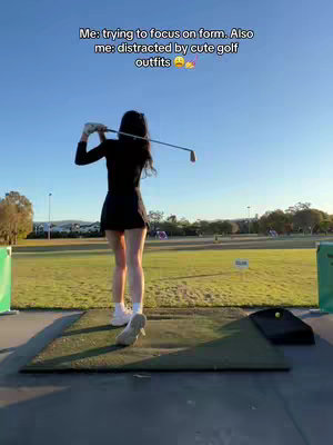 A woman in a black golf outfit is captured from the back mid-swing on a golf course. The sky is clear blue. Text overlayed at the top says 'Me: trying to focus on form. Also me: distracted by cute golf outfits'.