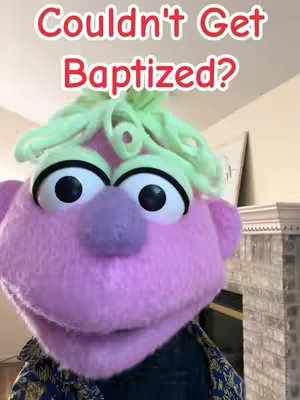 A close-up shot features a pink puppet-like character with large, expressive eyes, a purple nose, and green curly hair. The text overlay reads "Couldn't Get Baptized?" in a red, rounded font.