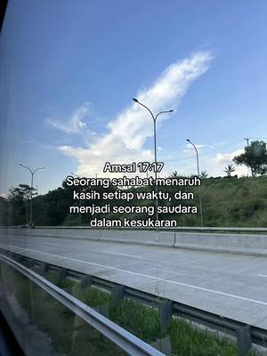 A daytime shot features a highway visible through a window or transparent surface, with a bright blue sky and some clouds in the background. Text overlayed on the image provides a Bible verse. The image has a natural, outdoor setting, with the highway and surrounding greenery creating a sense of place.