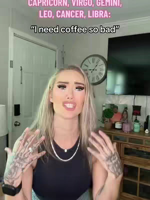 A woman with blonde hair and heavy makeup is in a well-lit room. Over her head is text in pink, and the woman is gesturing with her hands. The woman appears to be delivering a message, and the background includes a door, clock, and other decorative items.