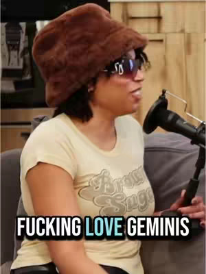 A woman with a brown fur hat, sunglasses, and a cream-colored shirt is speaking into a microphone. The background has wood panels. Text overlayed: "FUCKING LOVE GEMINIS"
