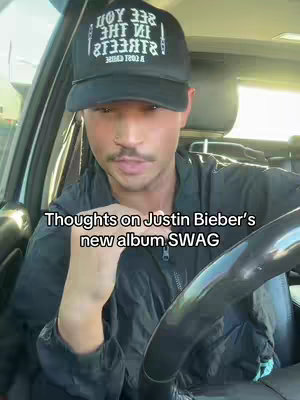 A man wearing a baseball cap and black jacket is sitting in a car. The text overlay on the image reads, Thoughts on Justin Bieber's new album SWAG.