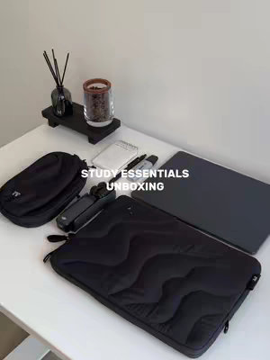 The cover image displays a bright, well-lit tabletop with various study essentials. A black laptop, a black laptop sleeve, a black carrying case, a small organizer, and stationary are arranged on the white surface. Additionally, there is a small black stand holding a vase with decorative sticks and a glass jar with coffee beans. The scene is clean and minimalist.