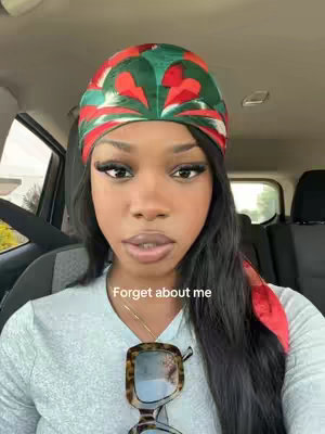 A woman in a car, looking at the camera with a composed expression. She's wearing a patterned headscarf with red, green, and white, and glasses hang around her neck. The image has warm tones and a soft focus with the text overlayed.