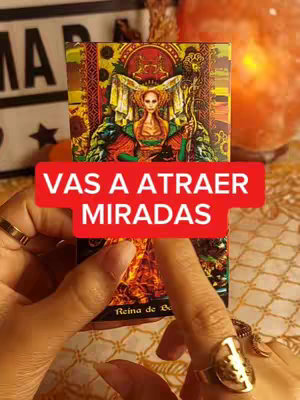 The cover image features a tarot card with the words "VAS A ATRAER MIRADAS" overlaid. The foreground shows hands with rings and a tarot card. The background includes other objects on a table. The color palette includes reds, oranges, and golds.