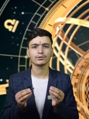 A young man with dark hair and a red bindi stands in front of a blurred background featuring astronomical elements. He wears a dark blue blazer over a white shirt, and has a lavalier microphone clipped to his jacket. He is gesturing with his hands, as if speaking or explaining something, and there's an astrological symbol of Libra present.