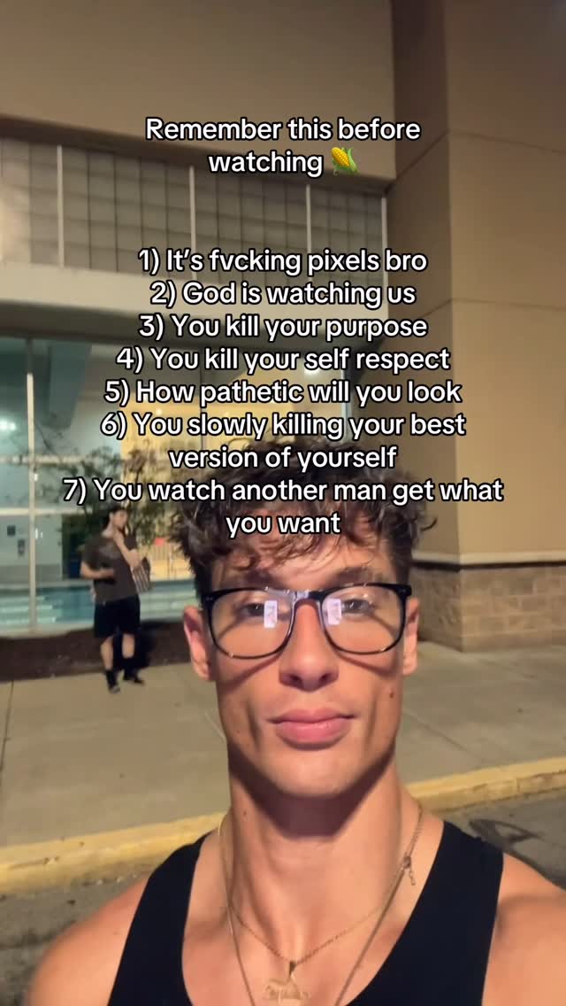 A selfie-style shot featuring a young man with short, tousled hair, wearing glasses and a black tank top. He has a slight smile and his eyes are focused on the camera. Behind him, there is some text overlaid on the image,  and some blurred figures walking in the background. The overall composition is bright, with the man centered, and the background elements providing context to the scene.
