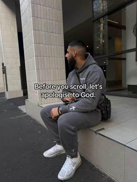 A man is sitting on a concrete ledge with his legs crossed. He is wearing a gray sweatsuit with white sneakers. Text overlayed on the image says 'Before you scroll, let's apologize to God.'