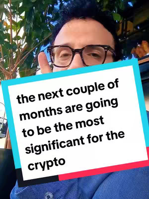 A man wearing glasses holds a phone. Overlaying the image is a white box with a blue and red stroke containing the text "the next couple of months are going to be the most significant for the crypto". The background seems to be of green foliages.