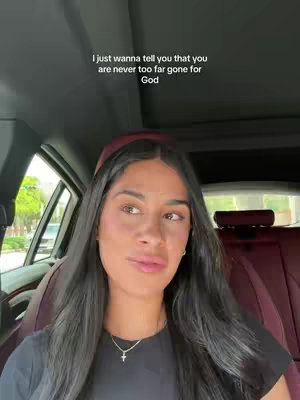 A young woman with long dark hair sits in the front seat of a car, looking slightly to her right. She's wearing a black shirt. Text overlayed on the image says, 'I just wanna tell you that you are never too far gone for God'.