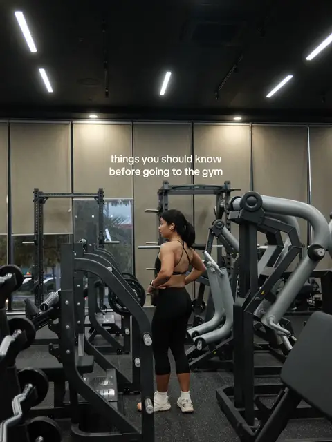A woman stands in a gym, viewed from the back, wearing a sports bra and leggings. The image is composed with gym equipment framing her and text that says 'things you should know before going to the gym.'