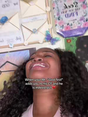 A selfie with a woman laughing with her head thrown back, showing her curly hair and open mouth. In the background are various decorative elements including white square envelopes and a poster with floral designs. Text overlay on the bottom left says 'When your Mr. God first adds you to his CF and he is indeed last'.
