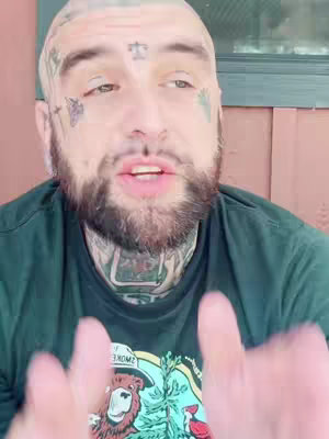 The cover image features a close-up shot of a man with a shaved head covered in tattoos. He is wearing a green t-shirt with a design that includes a bear, and is gesturing with both hands, appearing to talk. The background has a red-brown wall and a window.
