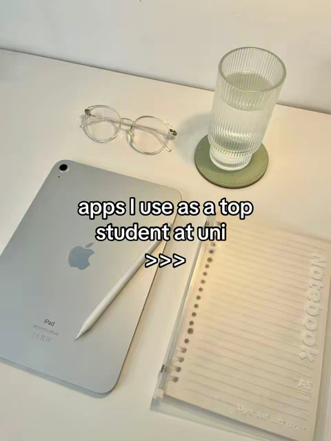 The image features a minimalist aesthetic with study-related items. A silver iPad rests on a white surface, with a white stylus next to it. Clear-framed glasses and a clear glass filled with water sit nearby. A notebook with visible lined paper is positioned to the right, and the whole setup is against a clean white background.