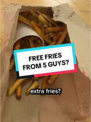A paper bag overflowing with golden-brown french fries. A white cup is visible among the fries which are the main focus. Overlay text on a colored rectangles states free fries from 5 guys?, extra fries. This setup suggests a food review or marketing analysis.