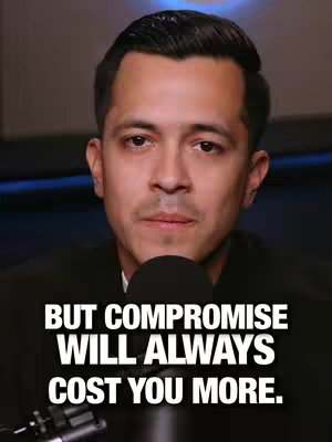 A medium shot focuses on a man's face against a blurred background. The man is wearing a black top. A microphone is positioned below his mouth. Bold white text overlays the lower part of the image.