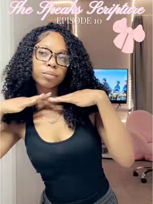 A woman with curly dark hair and glasses poses in front of a camera. The overlay includes text "She Speaks Scripture" and "Episode 10", along with a pink bow. The background shows a wall with a TV and a blurry image.