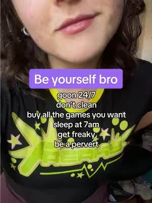 A selfie from the chest up. The subject has fair skin, short, wavy brown hair, with a black t-shirt that has a neon green design. A purple rectangular box at the top of the image contains text: 'Be yourself bro'. Below this text, there is a list of phrases in white that includes the phrases 'goon 24/7', 'don't clean', 'buy all the games you want', 'sleep at 7am', 'get freaky', and 'be a pervert'.