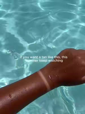 A person's arm is shown in clear water, with a visible tan line from the sun and a text overlay.