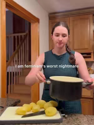 A woman in a teal dress is holding a pot and stands in front of a kitchen counter with cut potatoes and a knife. The hook text states 'I am feminism's worst nightmare.'