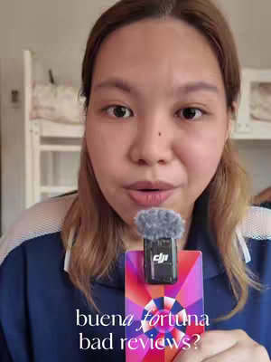 A woman with light brown hair holds a microphone in front of her mouth. She wears a dark blue shirt. The background is slightly blurred, with a bunk bed visible in the distance. The microphone is attached to a multi-colored card with an abstract design. The text overlay at the bottom of the image asks if there are bad reviews.