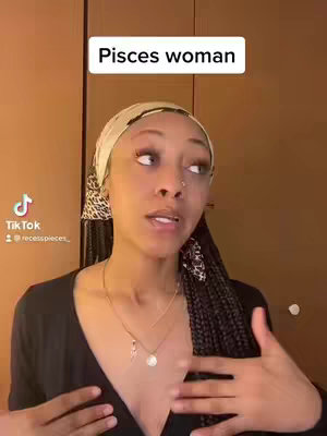 A woman with dark hair and a headscarf is speaking, with a text box above her head that says "Pisces woman". She is wearing a dark shirt with a gold necklace.
