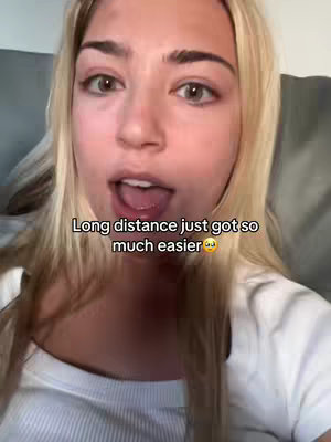 A selfie-style video shows a fair-skinned woman with long blonde hair against a blurred background. The woman is looking at the camera with her mouth slightly open. Text overlayed on the screen reads, 'Long distance just got so much easier' with a crying emoji.