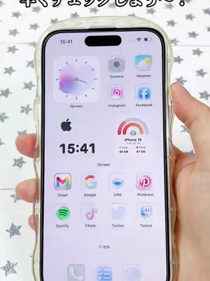 A smartphone screen displaying a custom home screen theme with various app icons and widgets including clock and battery status. The phone is held in a hand against a background with a star pattern.