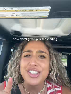 A medium shot captures a woman inside a car, smiling and speaking with an upward gesture. The background shows the car's interior, including the ceiling and a portion of the side window. The text overlay says 'pov: don't give up in the waiting.'