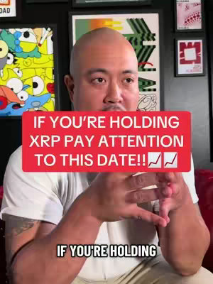 A man with a bald head is centered in the frame, looking directly at the camera. He is wearing a white t-shirt. A red banner across the man's chest displays the text, with two upward-trending graph icons at the end. Behind him, a wall with frames and artwork serves as the background.
