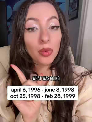 A woman with long, dark brown hair, wearing a light-colored shirt, and pointing her index finger towards the viewer. The background is slightly blurred with a painting and a wall. Overlayed text indicates 'WHAT WAS GOING' and list of dates.