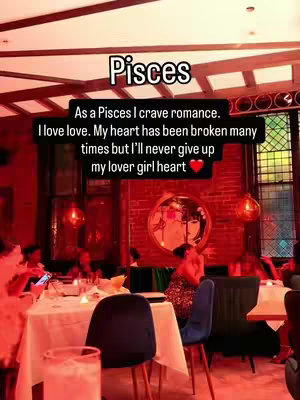 A brightly lit restaurant scene with several people seated at tables. A text overlay with astrological information is prominent, with a mirror in the background reflecting a woman's image.