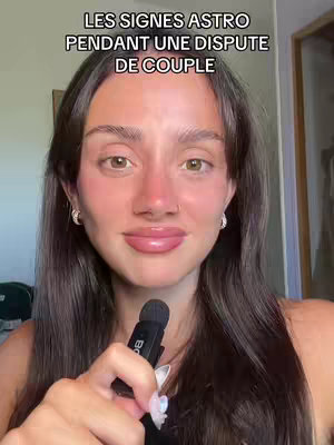 A young woman with long brown hair and a fair complexion is centered in the frame, holding a black microphone close to her face. She has soft features, with visible blush on her cheeks and lips. The background is slightly blurred, suggesting an indoor setting. The title is displayed above her head in a bold font.