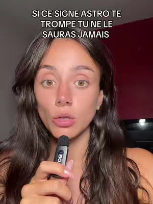 A woman with long brown hair and light skin is holding a microphone to her lips, looking directly at the camera. Text overlayed on the top of the image.