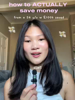 A young woman with long black hair and a fair complexion is centered in the frame. She's holding a small microphone. Above her, pink text reads, 'how to ACTUALLY save money' and below it reads 'from a 24 y/o w £100k saved'. The background is a blurry indoor setting.