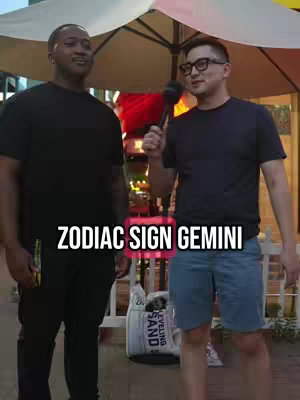Two men are standing outside, one holding a microphone and interviewing the other. Text overlay reads 'ZODIAC SIGN GEMINI.'