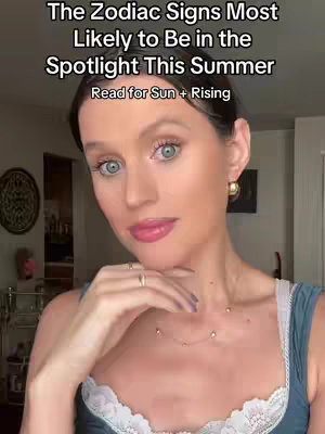 A woman with fair skin and light eyes is centered in the frame, looking slightly to the side. She has a slightly elevated hand near her chin, and layers of text appear above her head in the top left. Her lips are painted a soft pink, and she is wearing a blue tank top with a white lace trim and gold earrings.