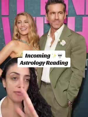 The cover image shows a woman in the bottom foreground pointing upward while looking at the viewers. In the background is a picture of a smiling Blake Lively and Ryan Reynolds. The image has a white text box in the middle with the words "Incoming Astrology Reading" in a bold text. There is a skull emoji next to the text. The background is pink.