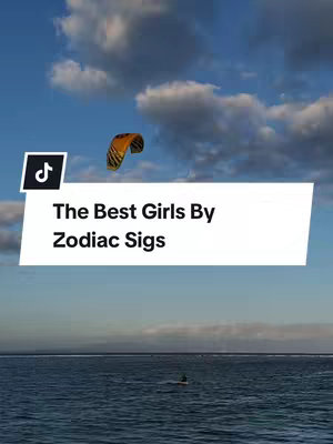 The cover image shows a blue sky with puffy white clouds. A kite with a yellow and orange design is visible in the sky. The video features a text overlay inside a white rectangle that reads "The Best Girls By Zodiac Sigs". Below, the ocean surface is visible, with a silhouette in the water.