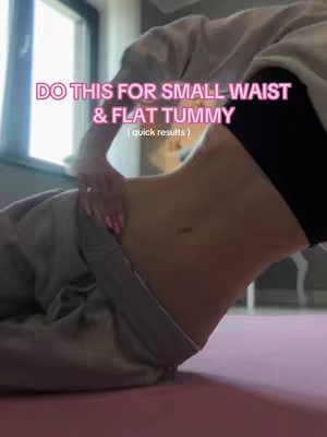The image shows a person's midsection from a slightly elevated angle, emphasizing the abdominal area. The person is wearing a black sports bra and gray sweatpants, and is leaning back slightly. The text overlay highlights the workout's goals. The background is a soft and diffused space, potentially inside with a muted palette, and a pink mat below suggests a workout area for indoor exercise.