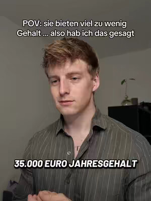 A young man in a grey-green shirt is centered in the image, looking slightly to the left. Above his head, white text reads, “POV: sie bieten viel zu wenig Gehalt ... also hab ich das gesagt”. Below him, another white text overlay reads, “35.000 EURO JAHRESGEHALT”. The background is a muted grey wall.