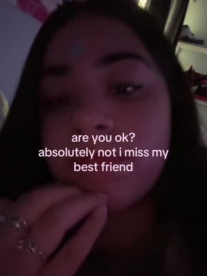 A close-up shot of a young woman with dark hair, appearing to be recording a video. The lighting is dim, and the background is out of focus, emphasizing her face. Text is overlaid on the image.
