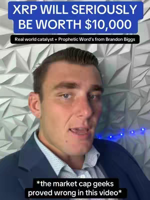 The cover image shows a man in his late 20s or early 30s, with short, dark hair styled neatly, and a clean-shaven face. He is wearing a dark blue suit jacket over a light blue patterned shirt. The background consists of a textured, geometric wall pattern. The top of the image features a dark blue banner with white text proclaiming "XRP WILL SERIOUSLY BE WORTH $10,000". Another smaller, black banner below it contains the text "Real world catalyst + Prophetic Word's from Brandon Biggs". At the bottom of the frame, there's a smaller black banner reading '*the market cap geeks proved wrong in this video*'. The man is looking directly at the camera with a slight smile, suggesting a confident and engaging demeanor. The overall composition is a frontal shot, focusing on the man's head and upper body.
